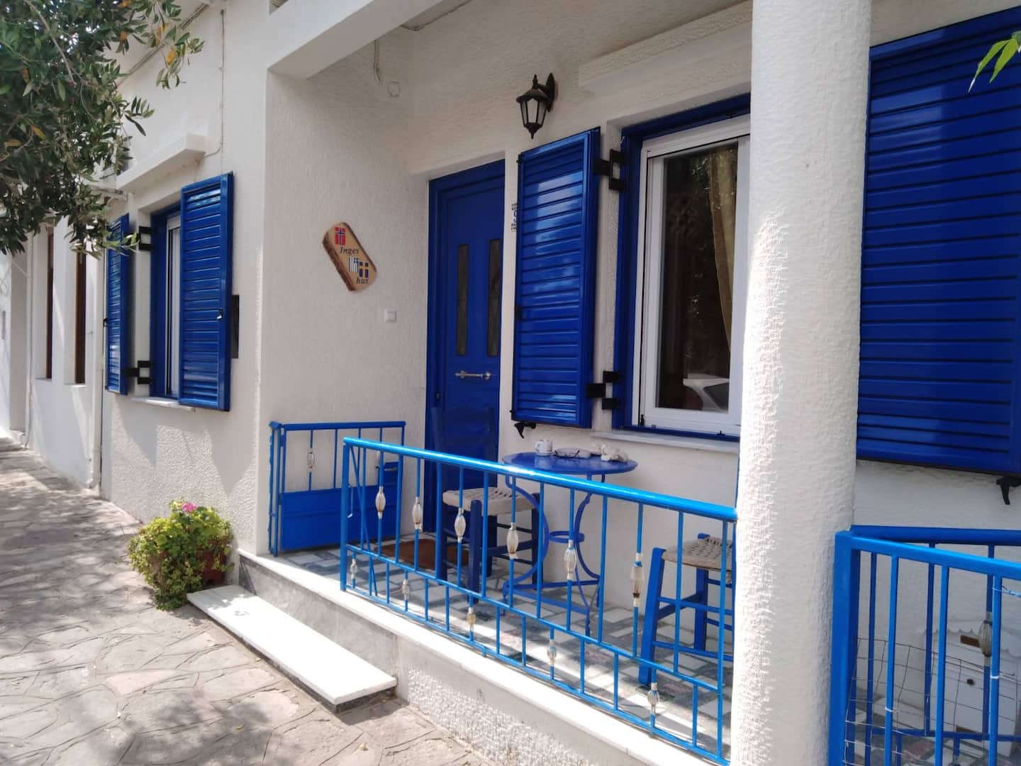 A whitewashed Greek island house with blue shutters and bougainvillea overlooking Pythagorio harbor in Samos